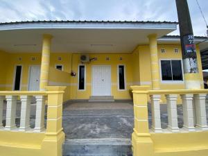 哥打丁宜BARAKAH HOMESTAY的黄色的建筑,有白色的门和柱子