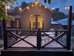 戴尔斯福特Daylesford - Frog Hollow Estate -THE COTTAGE - enjoy a relaxing and romantic night away in our gorgeous little one Bedroom ROMANTIC COTTAGE under the apple tree with water views的房屋设有木门廊和两把椅子