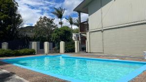 旺阿雷Aaron Court Motel Whangarei的房子前面的蓝色游泳池