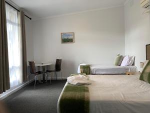 Meeniyan美尼炎汽车旅馆的酒店客房设有两张床和一张桌子。
