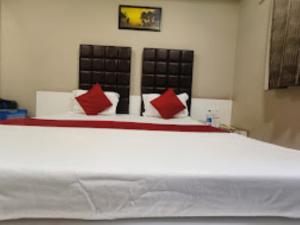 AshoknagarHotel Ahinsa Palace, Ashoknagar的一间卧室配有一张带红色枕头的大床