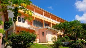 圣乔治Bougainvillea Apartments的一座橘色和白色的建筑,前面有树木