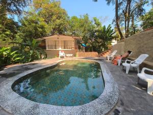 西奥利姆Greek "Jungle Villa", Thalassa Road, Standing alone 3bhk villa with pool的一个带椅子的庭院和房子的游泳池