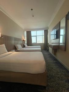 麦加Nawazi Towers Hotel的酒店客房设有两张床和大窗户。