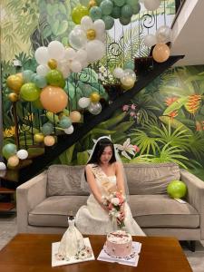 河内FlowerGod PentStudio WestLake Tay Ho Hanoi的坐在长沙发上,穿着婚纱的女人,配蛋糕