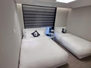 首尔HOTEL THE DESIGNERS LYJ SUITE YEOKSAM的配有2张床的带白色床单和枕头的客房