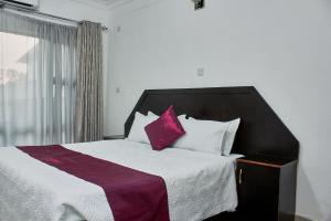 ZombaMango Lodge Zomba的一间卧室配有一张大床,提供紫色和白色枕头