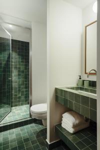 巴黎Edgar Suites - Bouchardon的浴室设有卫生间和绿色瓷砖淋浴。