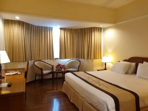 胡志明市Ramana Saigon Hotel的酒店客房带一张床、一张桌子和椅子