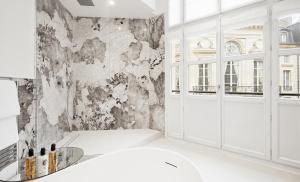 巴黎皇宫大酒店的浴室配有白色浴缸和大理石墙。