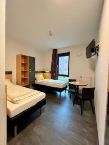 明斯特艾希青年旅舍的客房设有两张床、一张桌子和一台电视机。