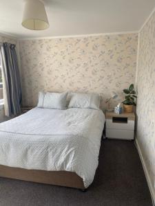 布伦海姆Stay@10的一间卧室配有一张带花卉图案墙壁的床