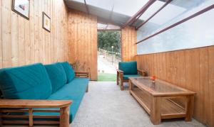 西姆拉Treebo Trend Daak Bangla Retreat With Mountain View的客厅配有蓝色的沙发和桌子