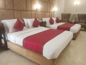 白沙瓦Shelton Accommodator的红色和白色的酒店客房内的两张床