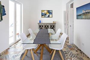 塔维拉Alagoa Apartments的一间带桌子和白色椅子的用餐室
