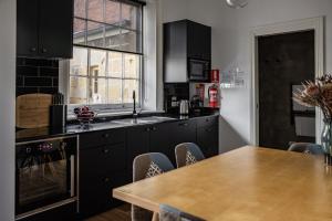 霍巴特圣殿精品公寓的厨房配有黑色橱柜和木桌