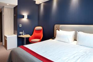 灵斯海姆Holiday Inn Express - Ringsheim, an IHG Hotel的酒店客房,配有一张床和一张红色椅子