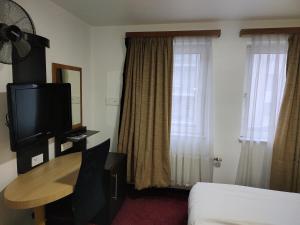 布鲁塞尔常青酒店的酒店客房设有床、桌子和电视。