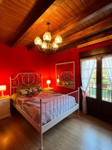 La Casa de Fefita (Stone house in a privileged environment 35 km from Bilbao)的一间卧室配有一张红色墙壁和吊灯的床。