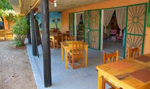 MbodièneAuberge Plein Soleil的餐厅设有木桌、椅子和彩色玻璃窗。