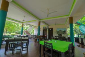 锡吉里亚The Green Heaven Resort的用餐室配有绿色的桌椅