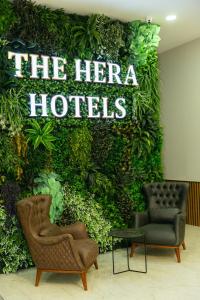 伊斯坦布尔The Hera Business Hotels & Spa的绿色的墙,有两把椅子和英雄酒店的标志