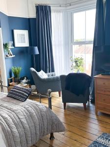 马伯斯View at 142的卧室拥有蓝色的墙壁,配有一张床和椅子