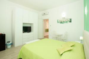 多穆斯德马里亚Affittacamere LE RONDINI的一间白色的卧室,配有绿色的床和电视