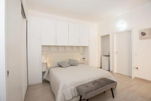 多穆斯德马里亚Affittacamere LE RONDINI的白色卧室设有一张大床和长凳