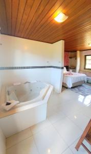 蒙特韦尔迪Chalés Leopoldo em Monte Verde的带浴缸和床的大型浴室