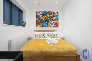 曼彻斯特Stylish, Modern 4bd - Etihad - Games - Parking - EV的卧室配有一张黄色的床,墙上挂着一幅画