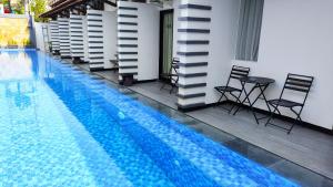 PademabuOdaita Hotel Pamekasan Madura的一座带椅子和桌子的游泳池位于大楼旁