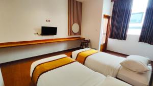 PademabuOdaita Hotel Pamekasan Madura的酒店客房设有两张床和一台平面电视。