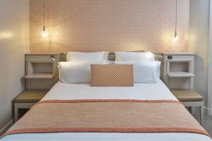 巴黎维克艾菲尔酒店的一张带白色枕头和橙色墙壁的床
