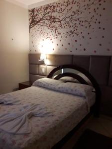 索罗卡巴LOFT NOVO CONFORTÁVEL的卧室配有一张床铺,墙上挂着一棵树