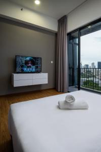 乔治市Penang KTHOME Beacon Executives suite的卧室配有一张床铺,墙上配有电视