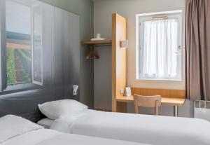 布尔日B&B HOTEL Bourges 1的酒店客房设有两张床、一张书桌和一个窗户。
