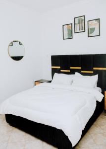 达累斯萨拉姆LM Apartments的一间卧室配有一张白色大床和黑色床头板