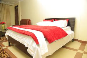 恩德培AIRPORT HOTEL Entebbe的一间卧室配有一张床铺,床上铺有红色毯子