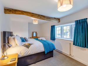 Caldbeck3 Bed in Caldbeck 86087的一间卧室配有一张带蓝色窗帘的床和一扇窗户