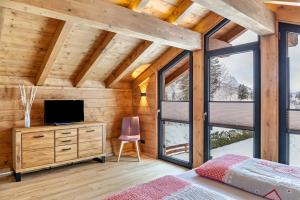 加尔米施-帕滕基兴Chalet Aus Holz的一间卧室设有一张床,木墙上配有电视。