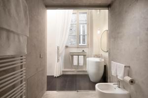 乌尔比诺Palazzo Giusti Suites and Spa的一间带水槽和卫生间的浴室以及窗户。