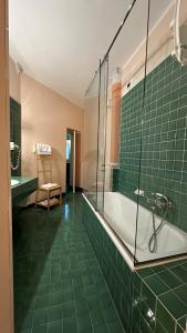 博洛尼亚罗马酒店的绿色瓷砖浴室设有浴缸和椅子