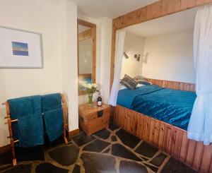ElgolTigh Mairi at Mary's Thatched Cottages的一间卧室配有一张带蓝色毯子的木床
