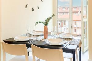 都灵Vista Mole, Centro a 15 min - Luxury Suites & fast WiFi的餐桌,配有白色的盘子和椅子