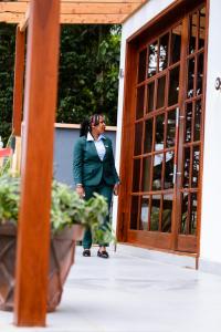 阿鲁沙Greenside Hotel的站在门前身穿着绿色衣服的女人