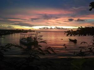 麦岛The Hut Koh Mak Sea View的日落时分坐在水中的船