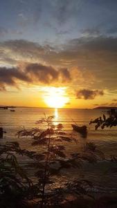 麦岛The Hut Koh Mak Sea View的海滩上的日落,在水中乘船