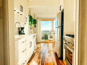 圣地亚哥Sunkissed Boho Hilltop Haven Apartment的厨房配有白色橱柜和硬木地板。