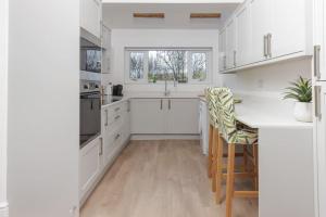 卡菲利82 Van Road的厨房配有白色橱柜和桌椅